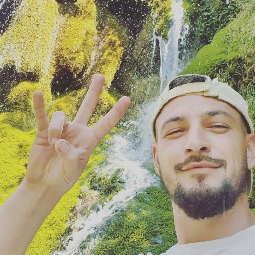Jessy Betti en repos actif dans la nature, casquette à l'envers, signe de la victoire